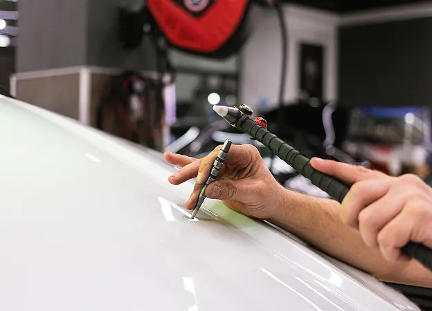 Carrossier réalisant le débosselage, des travaux de carrosserie et peinture dans un garage à Ris-Orangis proche d'Evry (91)